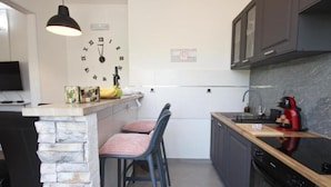 A modern kitchen with a stone accent wall, a clock, and a red mixer. - Delux Konavle Village Apartment (Konavle)