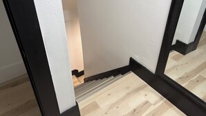 A staircase with a wooden floor and black trim, leading to a room with white walls.