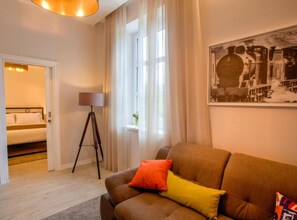 Ein modernes Wohnzimmer mit einer Couch, einer Lampe und einem Bett im Hintergrund.