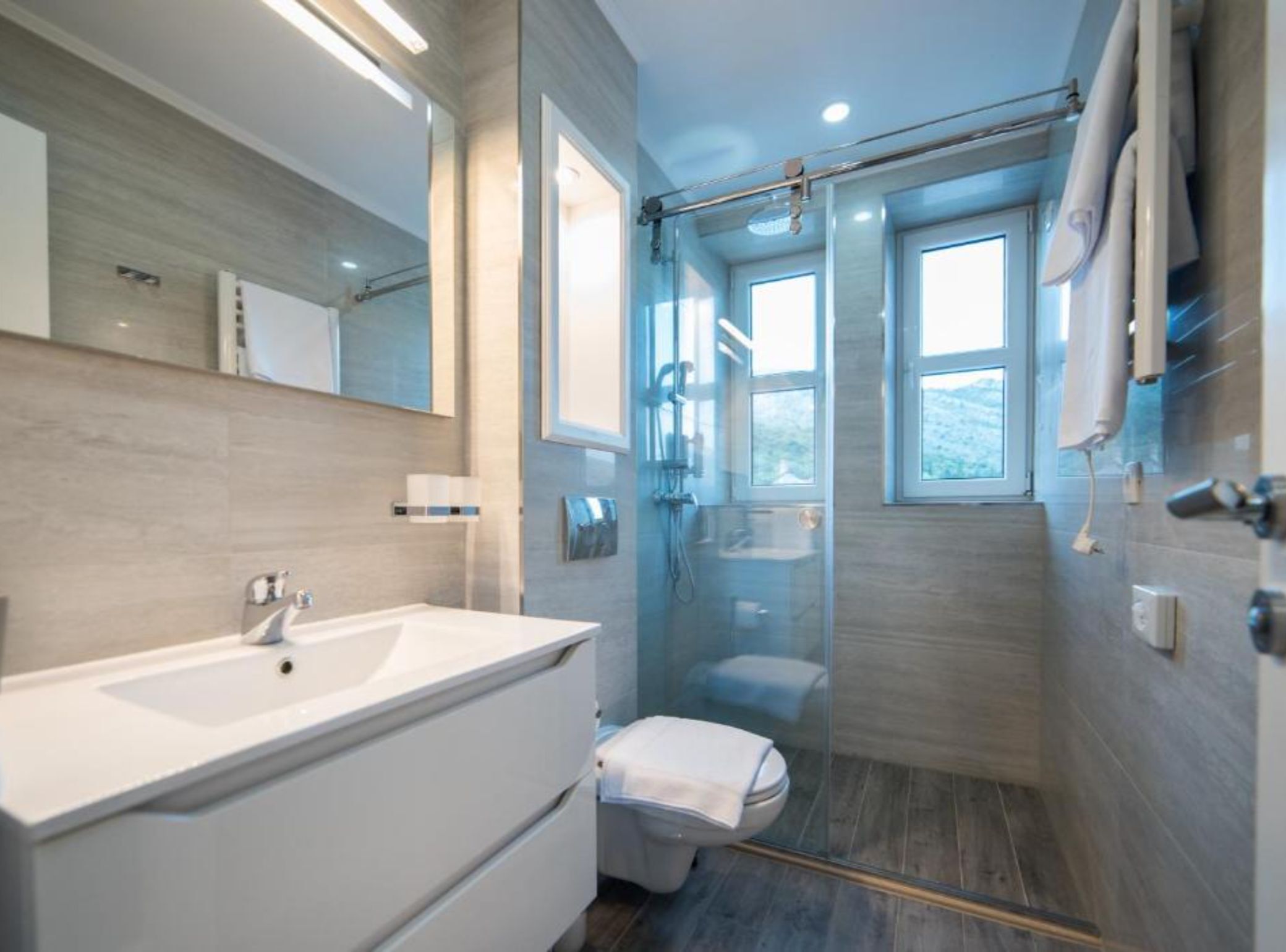 A modern bathroom with a glass-enclosed shower, a large white sink, and a toilet.