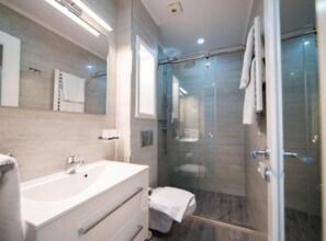Ein modernes Badezimmer mit einer gläsernen Duschkabine, einem weißen Waschtisch mit Waschbecken und einer Toilette.