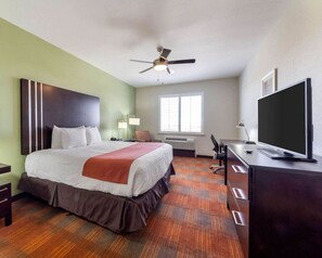 Une chambre d’hôtel équipée d’un lit, d’un bureau, d’une télévision, d’un ventilateur de plafond et d’une fenêtre.