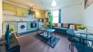 A compact living space with a kitchenette, a sofa, a coffee table, and a TV. - The Bristol Hidey-Hole (Bristol)