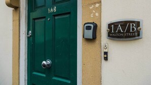 A green door with a 'LAB' sign above it, a '1A/B WALTON STREET' sign, and a doorbell on the wall. - The Bristol Hidey-Hole (Bristol)