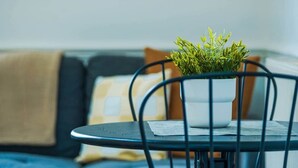 A dining table with a potted plant, a chair, and a sofa with cushions in a room. - The Bristol Hidey-Hole (Bristol)