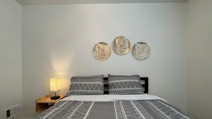 A bedroom with a bed, a nightstand, and three wall-mounted decorative items. - Tranquil 2-bedroom apartment with AC in Little Rock (Little Rock)
