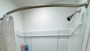 A modern bathroom with a walk-in shower, a built-in shelf with toiletries, and a shower curtain with a geometric pattern. - Tranquil 2-bedroom apartment with AC in Little Rock (Little Rock)