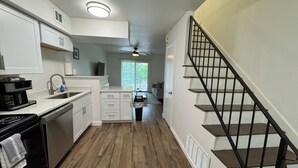 A kitchen with white cabinets, a dishwasher, and a stove. There is a staircase with black railings leading to another level. - Tranquil 2-bedroom apartment with AC in Little Rock (Little Rock)