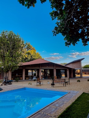 A poolside area with a brick building, outdoor seating, and a motorcycle. - Pousada Martins Turismo (Carolina)