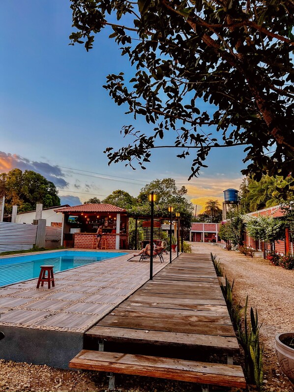 A pool area with a wooden deck, a bar, and a covered seating area. - Pousada Martins Turismo (Carolina)