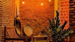 A room with brick walls, hanging light bulbs, a wooden chair, a table, and a potted plant. - Pousada Martins Turismo (Carolina)