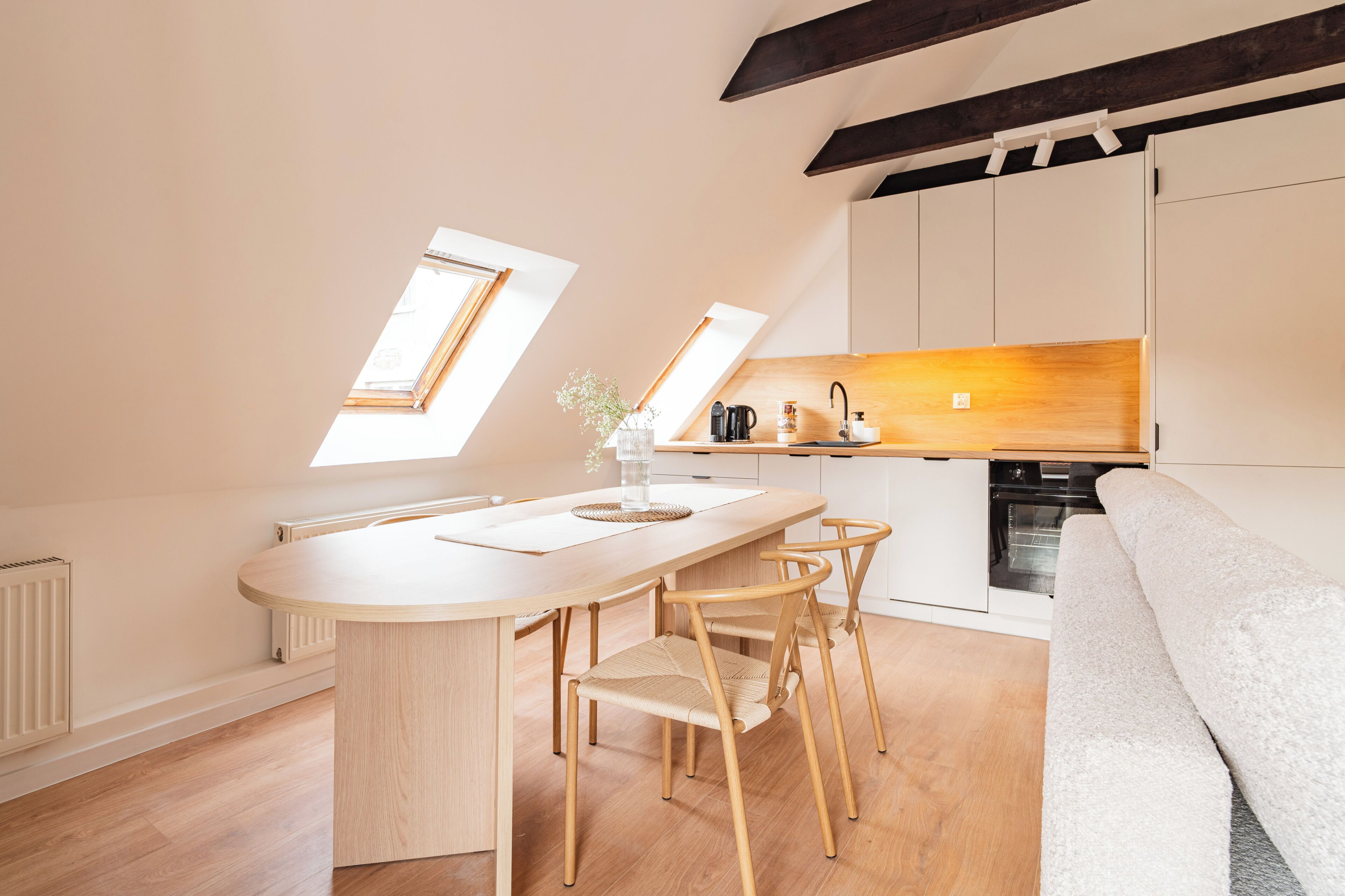 Una cocina moderna con una isla central, sillas de madera y un horno empotrado.