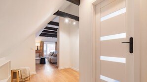 A modern interior with a wooden floor, white walls, a lofted ceiling, and a door with a handle. - RentPlanet - Apartamenty Raciborska (Gliwice)