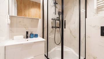 A modern bathroom with a glass-enclosed shower, a white sink, and a wooden vanity.