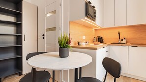 A modern kitchen with white cabinets, a round dining table, and black chairs. - RentPlanet - Apartamenty Raciborska (Gliwice)