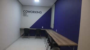 Ett rum med ett långt träbord, tre stolar och en blå accentvägg med orden ”COWORKING” och ”SKAPAR VI FRAMGÅNGSRIKA ARBETSMILJÖER” på.