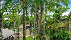 Un patio exuberante con palmeras, una piscina y un área de estar techada.