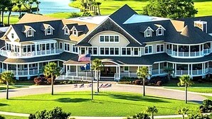 A large, multi-story hotel with a prominent American flag, a covered front porch, and a golf course in the background. - 3BR Seabrook Home, Pet Friendly, Near Beach-Pools, Golf, Equestrian and Tennis (Seabrook Island)