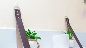 Une étagère de salle de bain avec une plante, un rouleau de papier toilette et un couteau.