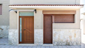 Un edificio con fachada de piedra, puerta de madera y ventana con contraventanas.