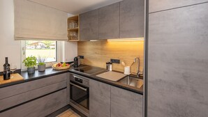 Una cuina moderna amb forn de mur, un rentapeus i una finestra amb vista a l'exterior.