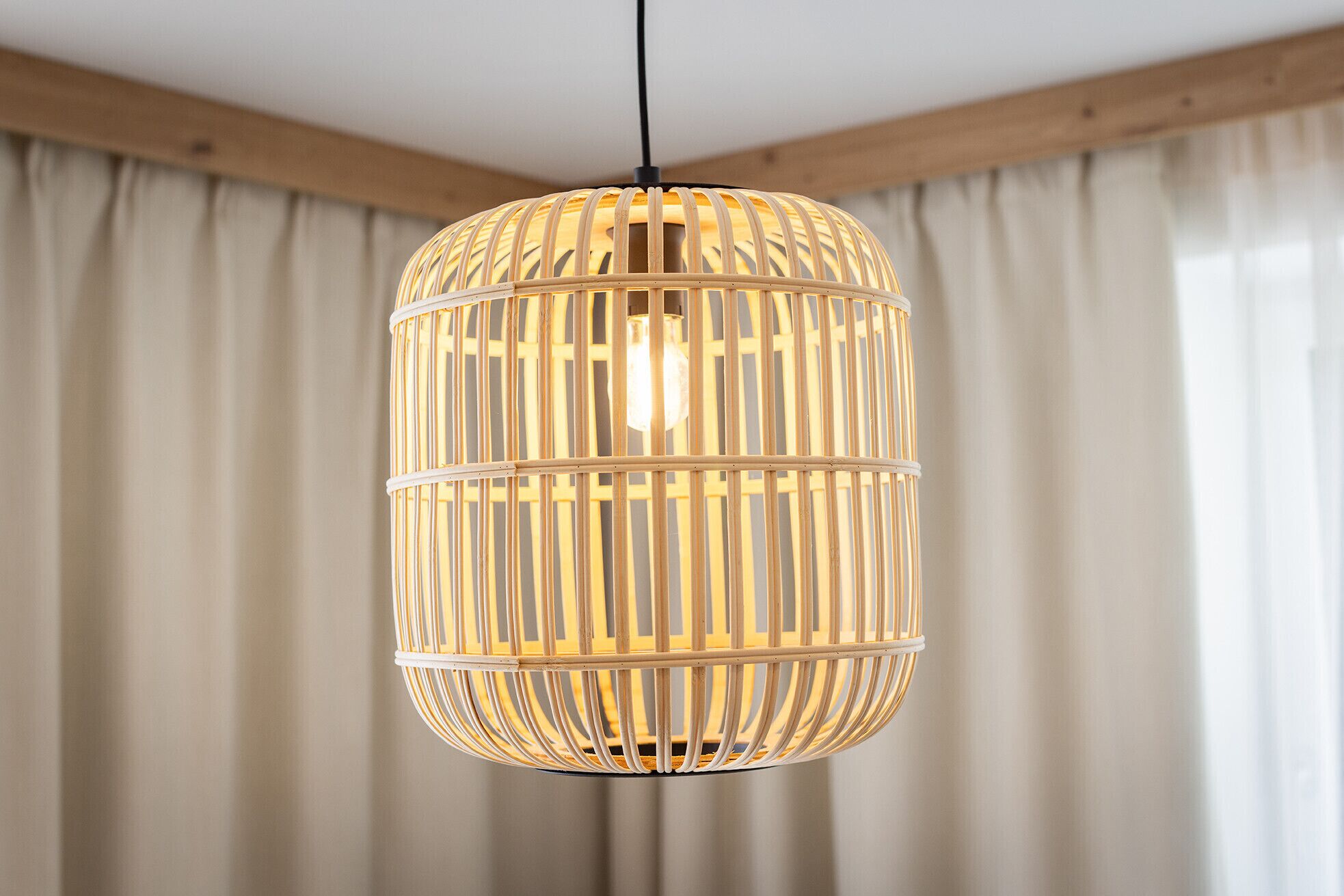 En hängande lampa med en cylindrisk design och vertikala lameller.