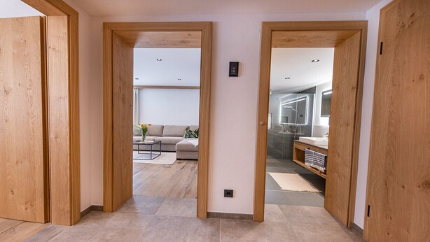 A hallway with wooden doors leading to a living area with a sofa and a coffee table. - Lennis Apartments - Top 2, Terrace, Mountain View (Bruck an der Großglocknerstraße)