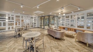 Un intérieur moderne avec un espace salon central, une cloison en verre et une vue sur l’intérieur à travers cette cloison.