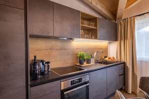 Eine moderne Küche mit eingebautem Backofen, einer Spüle und einem Holzregal über der Arbeitsfläche.