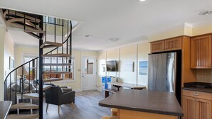 Uma cozinha moderna com uma ilha central, uma escada em espiral e uma área de refeições com vista.
