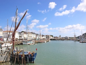 Ein Hafen mit vertäuten Booten, Gebäuden an der Uferpromenade und einem klaren Himmel.