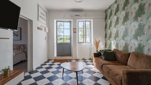 En stue med et ternet gulv, en brun sofa, et træbord og en grå dør.