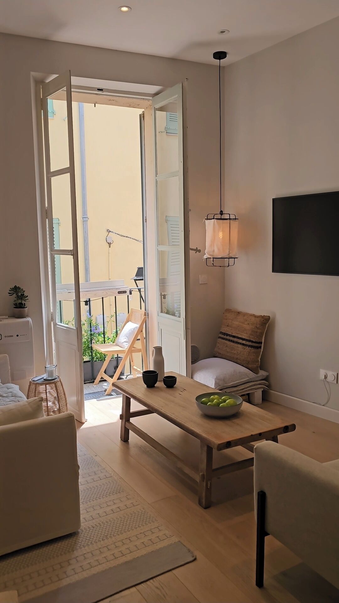 Ett modernt vardagsrum med ett soffbord i trä, en soffa, en fåtölj och en tv som är monterad på väggen.