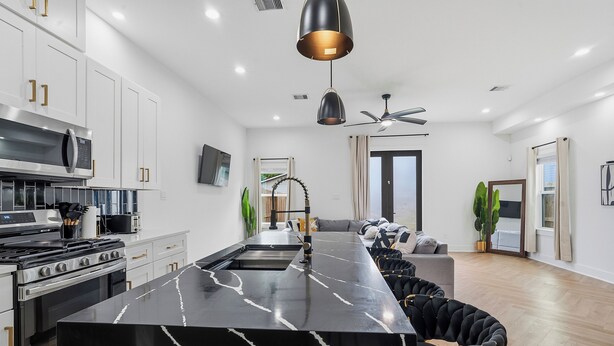 Une cuisine moderne dotée d’un îlot en marbre, d’appareils électroménagers en acier inoxydable et d’un ventilateur de plafond.