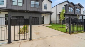 Un immeuble résidentiel doté d’un garage, d’une allée fermée par un portail et d’une pelouse bien entretenue.