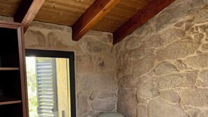 A room with a stone wall, a wooden ceiling, a chair, and a wooden cabinet.