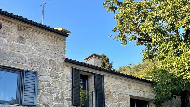 A stone building with a staircase, a table with chairs, and a tree.