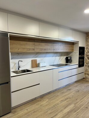 A modern kitchen with a built-in oven, a stainless steel sink, and a wooden countertop.