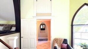 Une pièce avec un escalier, un fauteuil noir, un tapis à motifs et une fenêtre donnant sur un beau paysage.