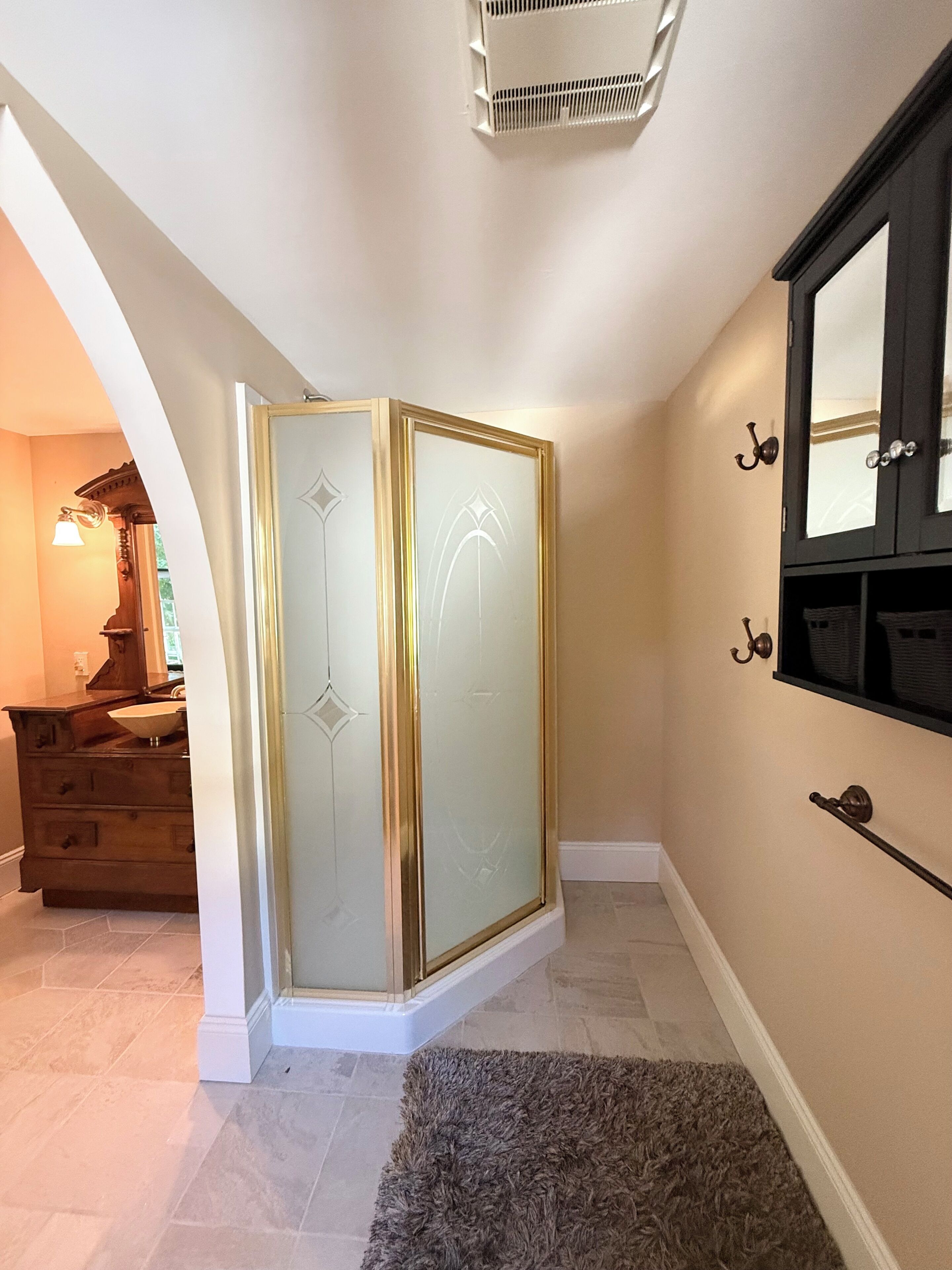 A bathroom with a vanity, a shower enclosure, and a mirror.
