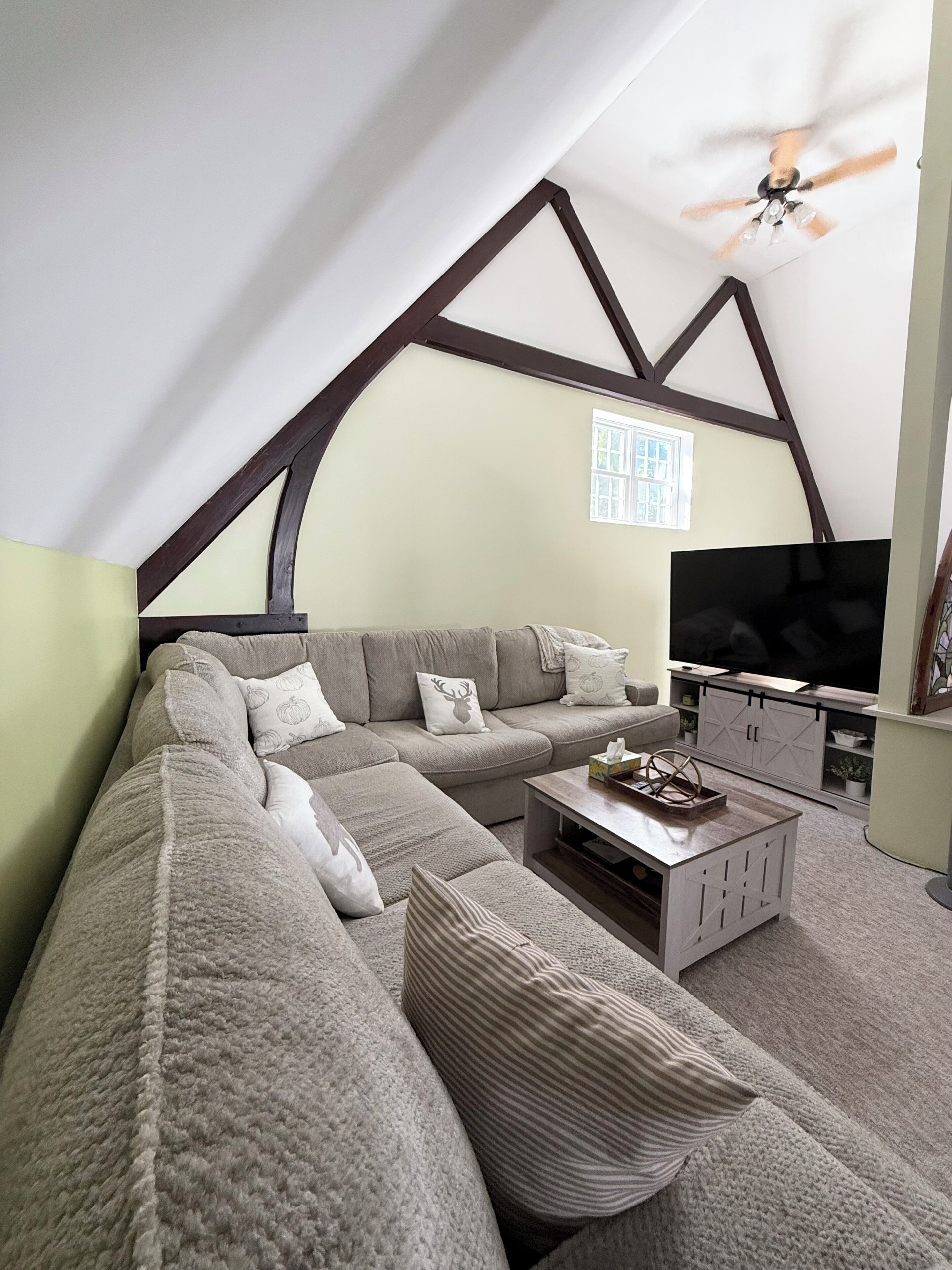 Un soggiorno moderno con un divano componibile, una televisione a schermo piatto e una ventola a soffitto.
