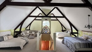 Une chambre située sous les combles, avec un plafond en voûte, un vitrail et deux lits.