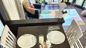 Une table à manger dressée avec des sets de table, des couverts et des bougies, entourée de chaises blanches.