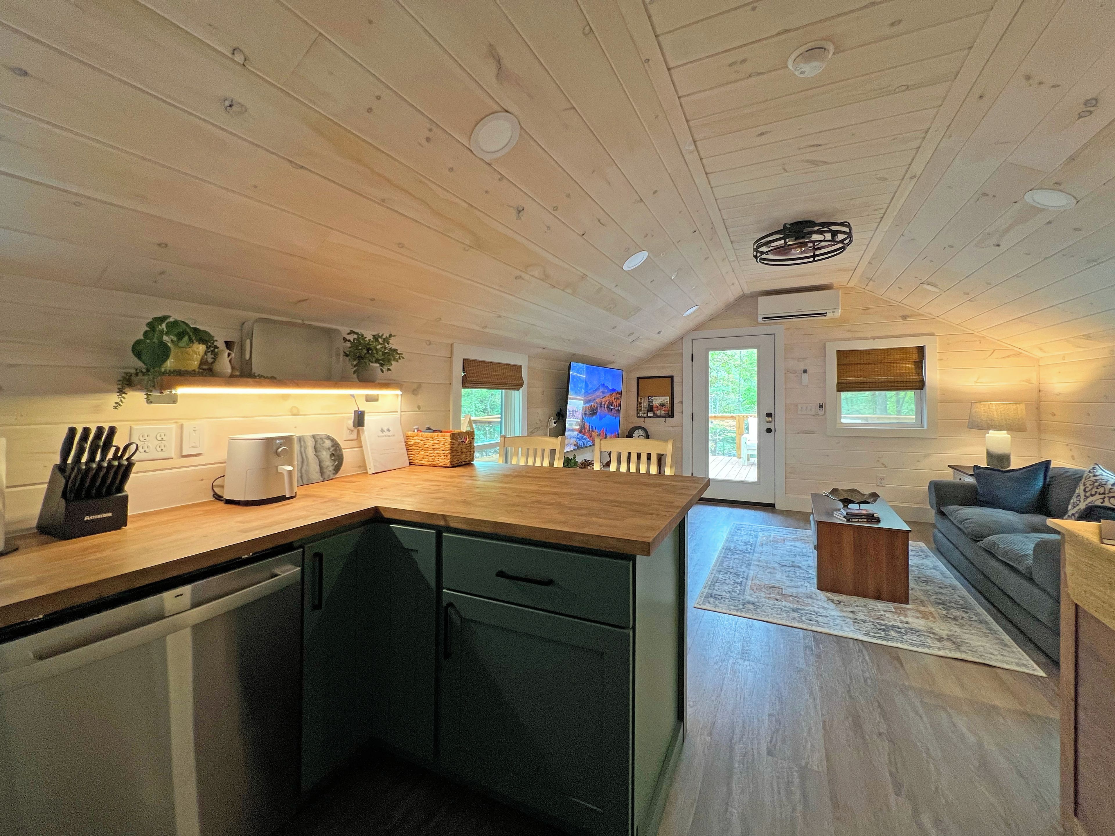 Una cocina moderna con armarios de madera, lavavajillas integrado y una zona de comedor con mesa y sillas de madera.