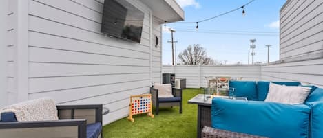 A backyard with a white house, outdoor furniture, a fire pit, and a children's game set.