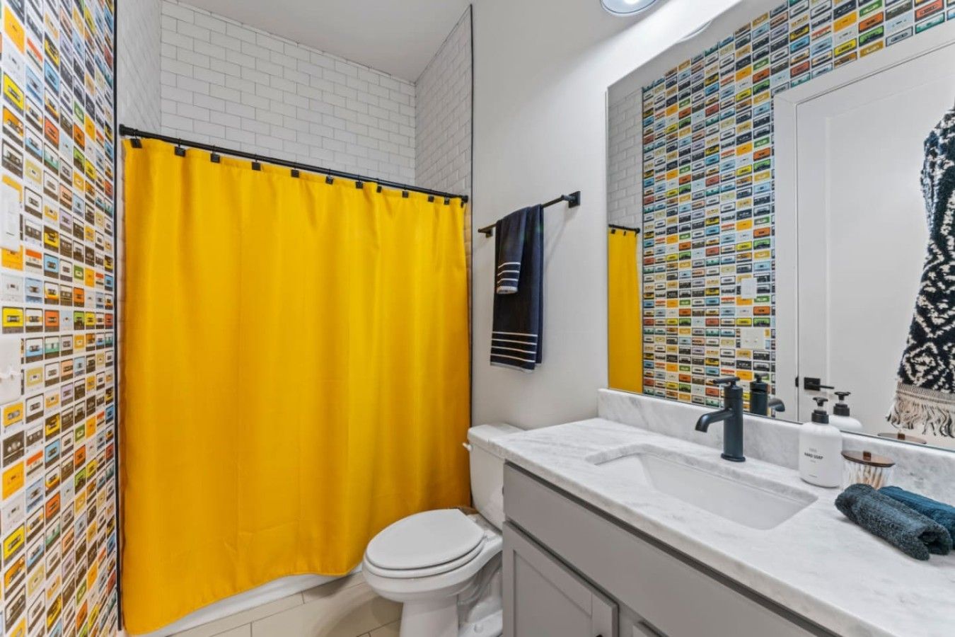 A bathroom with a yellow shower curtain, a white toilet, a sink with a mirror, and a towel rack.