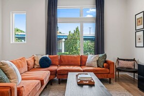 Una sala de estar con un sofá modular, una mesa de centro y vistas a un puente y follaje exterior.