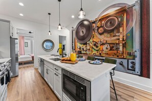 A modern kitchen with a central island, stainless steel appliances, and a decorative wall with mechanical elements. - Rhythm & Roots Retreat (Nashville)