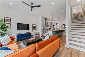 A modern living room with a sofa, a coffee table, a TV, and a ceiling fan. - Rhythm & Roots Retreat (Nashville)