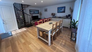 A modern kitchen with a dining area, wooden flooring, a staircase, and a TV. - House two minutes from the beach (barfleur)